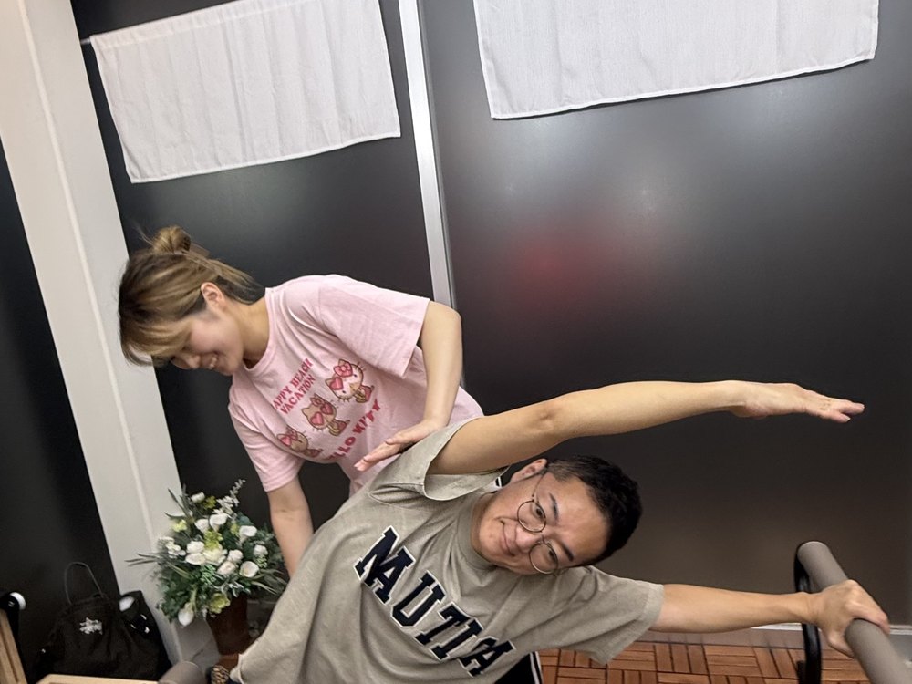 ユラ先生が両手で支えながら体側を伸ばす